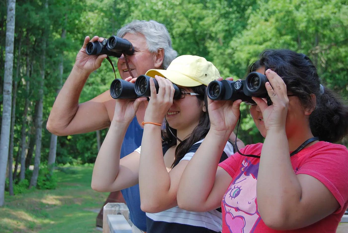 A grandfather and two girls scanning for birds through binoculars at Claytor Lake State Park, Virginia