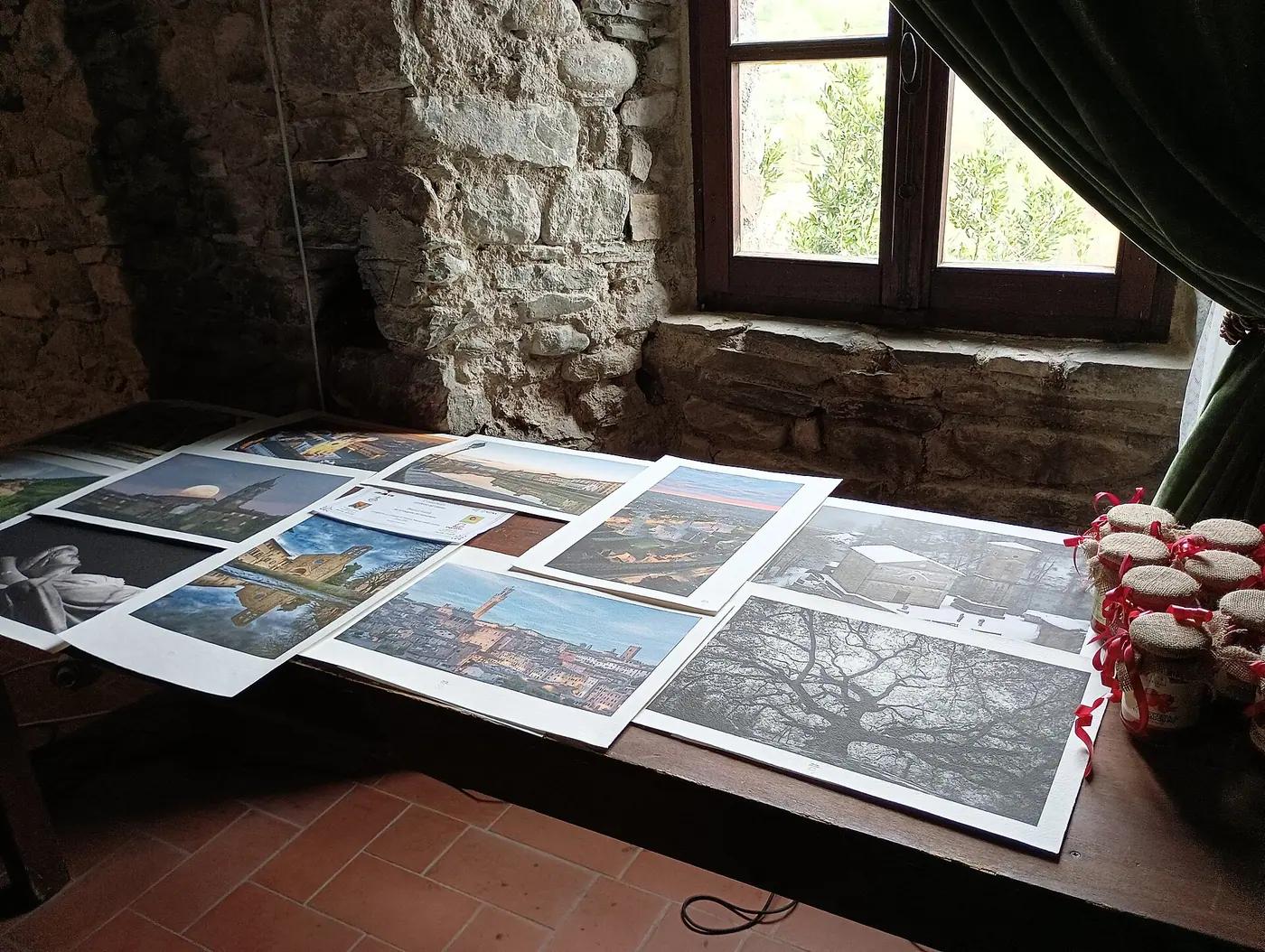 Photographic prints laid out across a wooden table beside a window