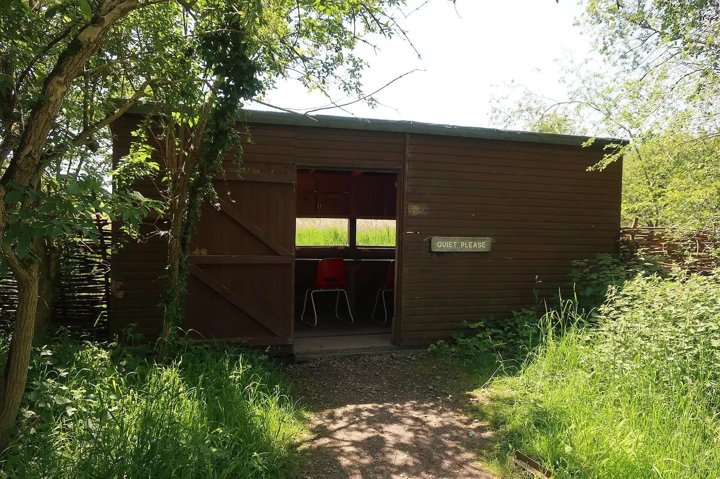 Wooden bird hide with a Quiet Please sign at an RSPB reserve