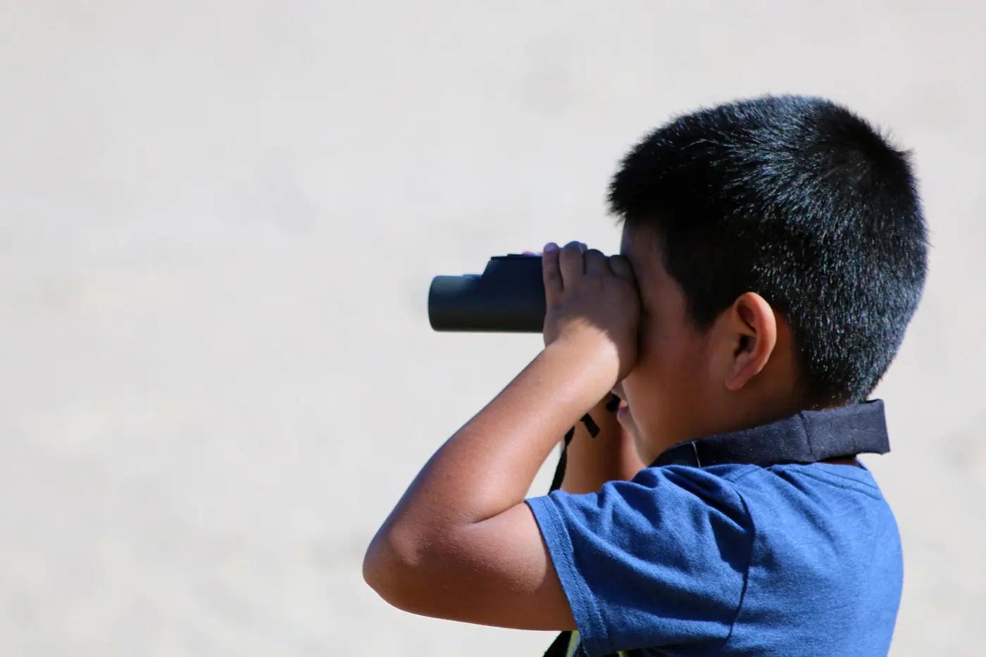 A young birder scanning with binoculars